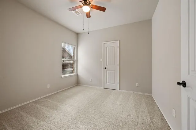 an empty room with a chandelier fan and windows
