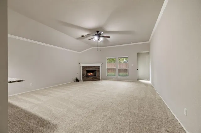 an empty room with fireplace and a ceiling fan