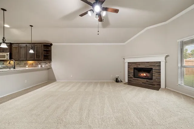 a view of an empty room with kitchen fireplace and a ceiling fan