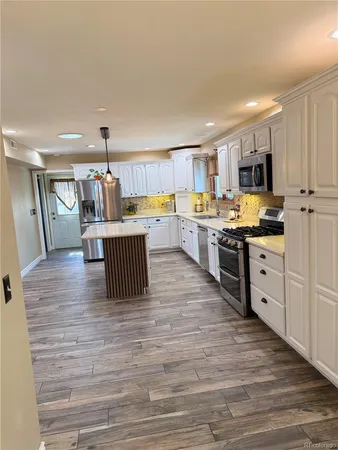 a kitchen with stainless steel appliances granite countertop a stove top oven a sink dishwasher and a refrigerator