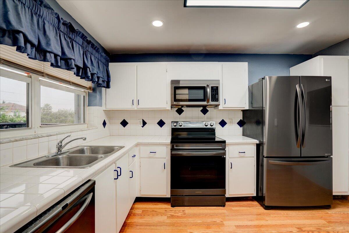 a kitchen with a sink cabinets stainless steel appliances and a window