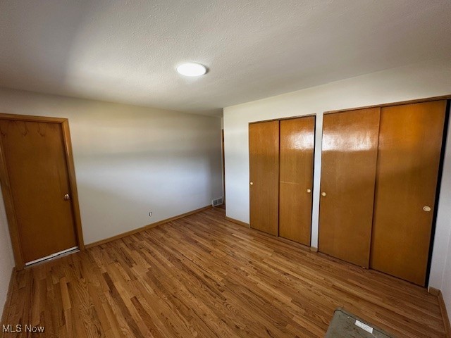8375 Royal Ridge Drive Parma, OH 44129 - Photo 4 of 12 Unfurnished bedroom featuring two closets, wood finished floors, and a textured ceiling