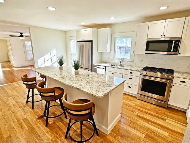a kitchen with granite countertop kitchen island wooden cabinets and stainless steel appliances