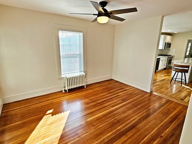 an empty room with wooden floor fan and windows