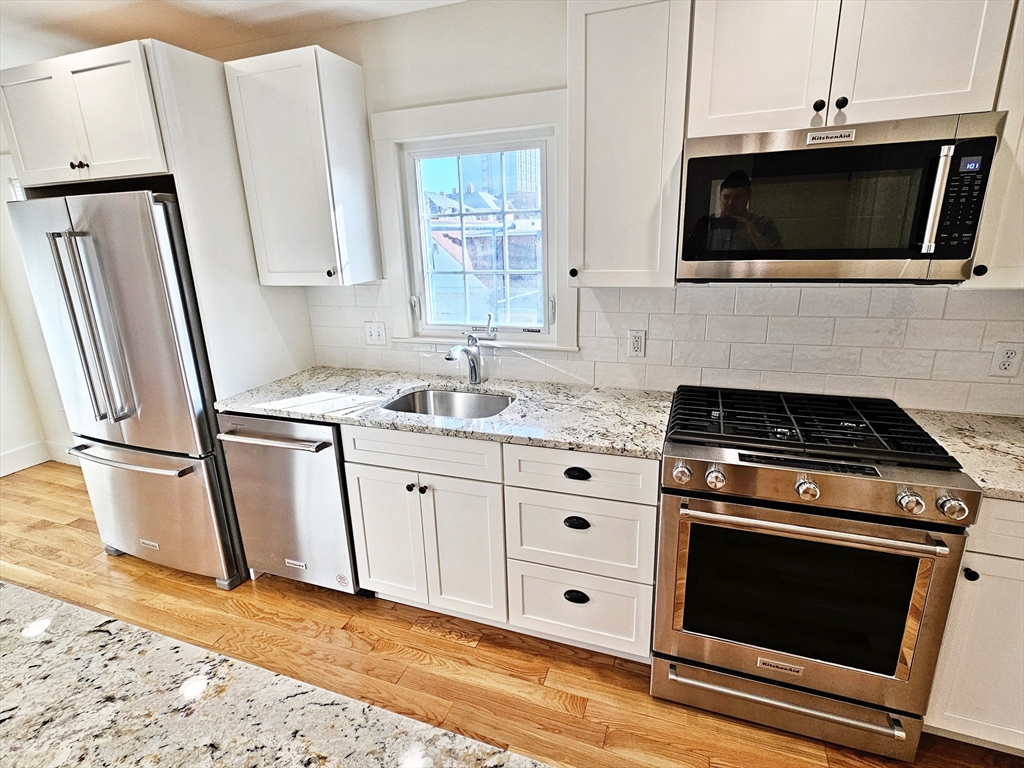 11 Channing Street, Unit 2 Newton, MA 02458 - Photo 2 of 27 a kitchen with granite countertop a stove microwave and sink