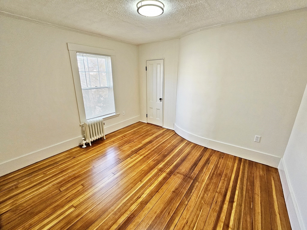 11 Channing Street, Unit 2 Newton, MA 02458 - Photo 21 of 27 a view of an empty room with wooden floor and a window