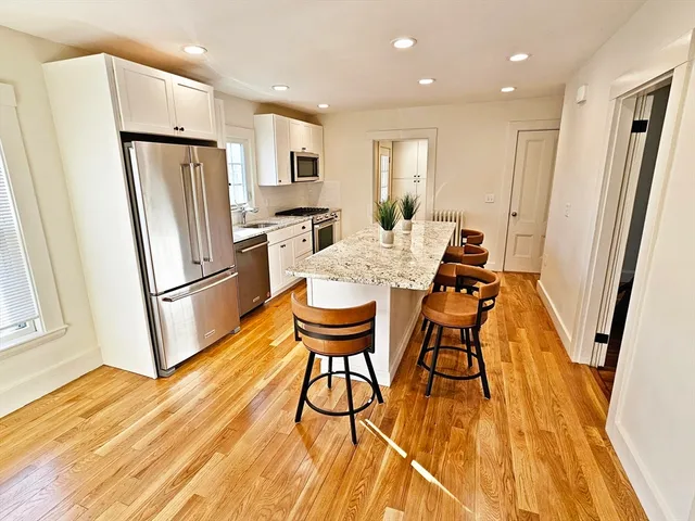 a kitchen with stainless steel appliances a refrigerator a sink dishwasher and a stove with wooden floor