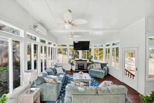 a living room with furniture large windows and wooden floor