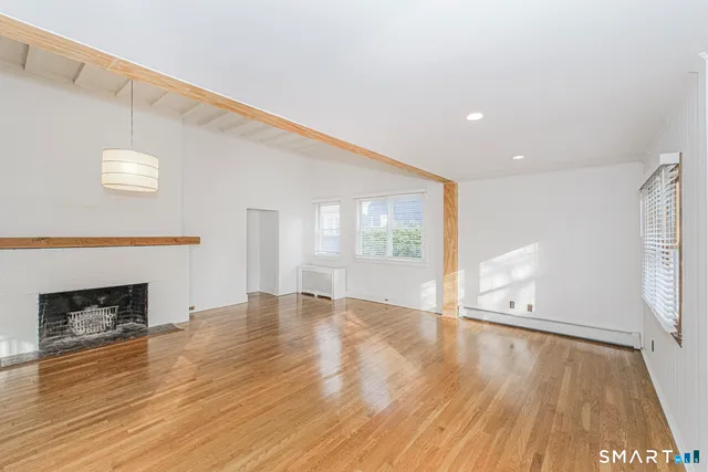 a view of empty room with wooden floor and fireplace