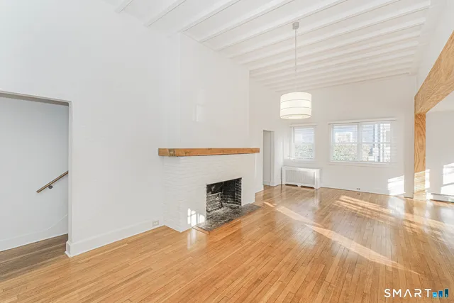 an empty room with wooden floor fireplace and windows