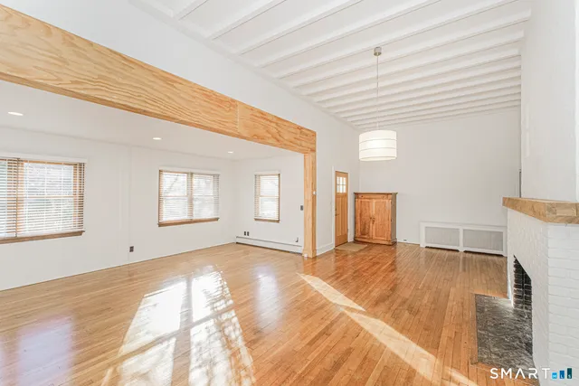 a view of empty room with wooden floor and window
