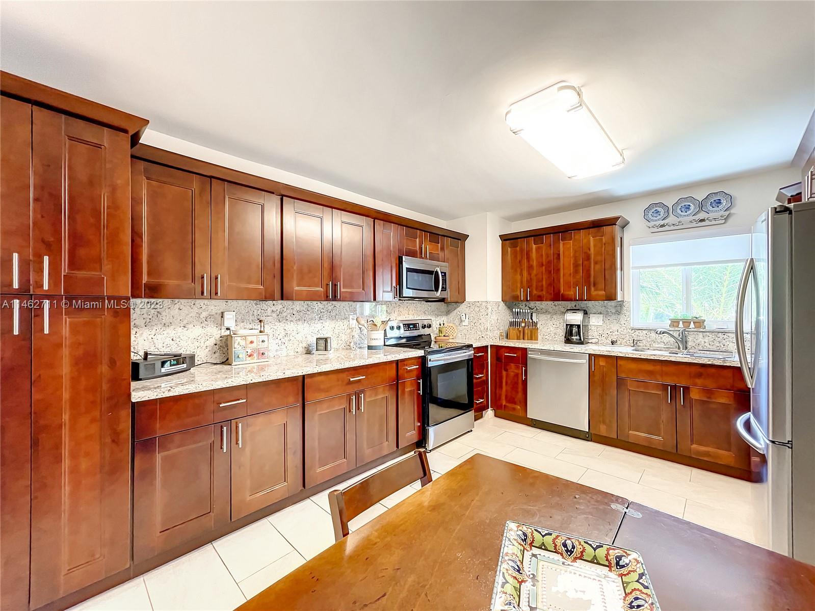 9035 Southwest 48th Terrace Miami, FL 33165 - Photo 12 of 37 a large kitchen with stainless steel appliances granite countertop wooden cabinets a sink and dishwasher