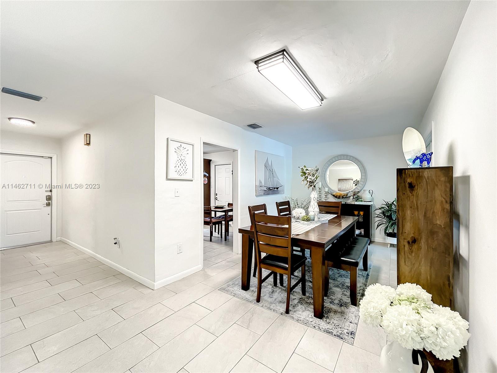 9035 Southwest 48th Terrace Miami, FL 33165 - Photo 5 of 37 a view of a dining room and livingroom with furniture wooden floor a rug a painting and a chandelier