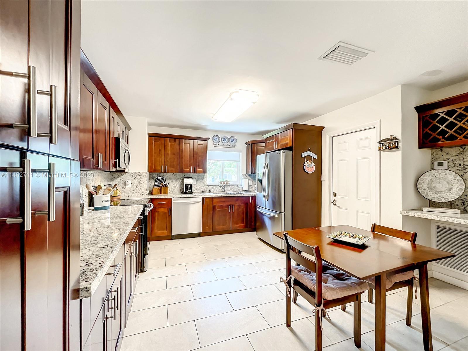 9035 Southwest 48th Terrace Miami, FL 33165 - Photo 10 of 37 a kitchen with stainless steel appliances kitchen island granite countertop a table chairs and a refrigerator