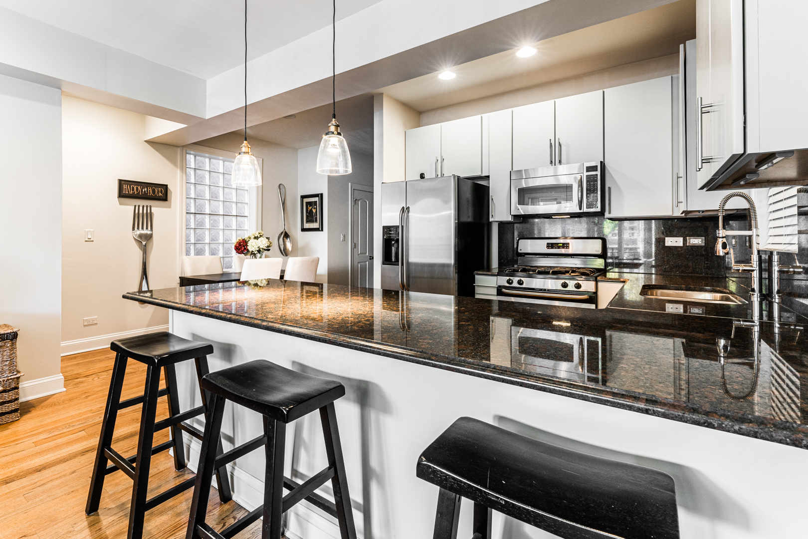 844 West Erie Street, Unit 1 Chicago, IL 60642 - Photo 6 of 37 a kitchen with stainless steel appliances kitchen island granite countertop a table chairs microwave and sink