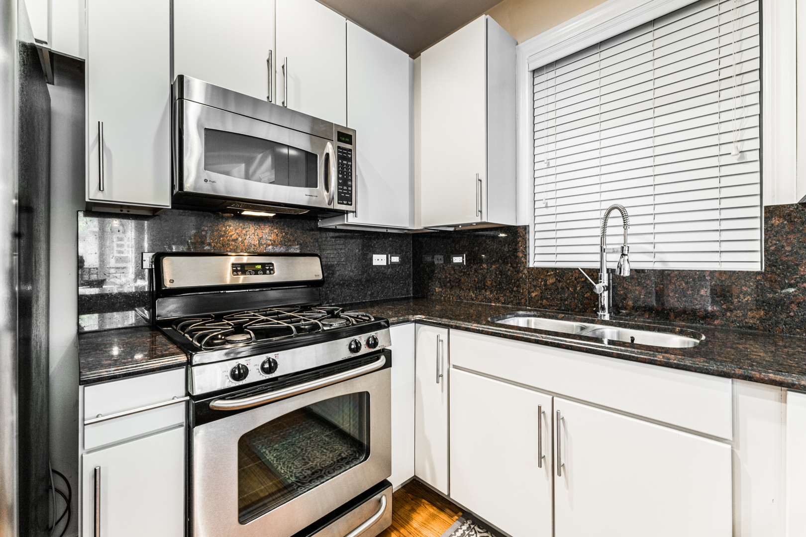 844 West Erie Street, Unit 1 Chicago, IL 60642 - Photo 10 of 37 a kitchen with granite countertop a stove a sink and a microwave