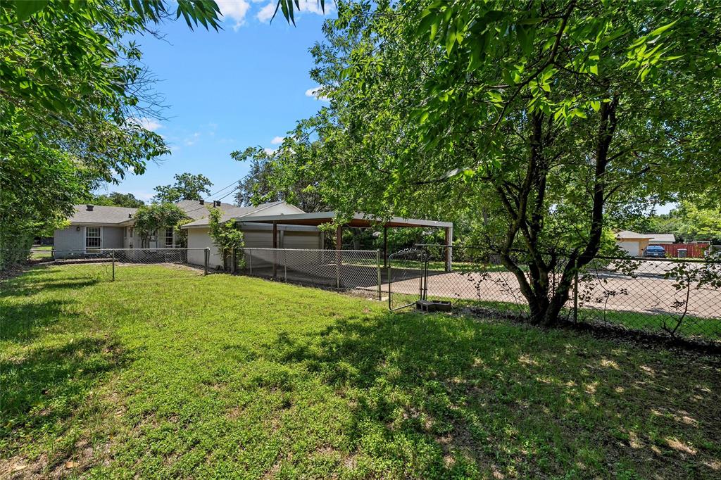 3225 Windsor Avenue Waco, TX 76708 - Photo 21 of 25 Spacious rear yard with a chain-link fence, mature trees, and a detached carport featuring a metal roof