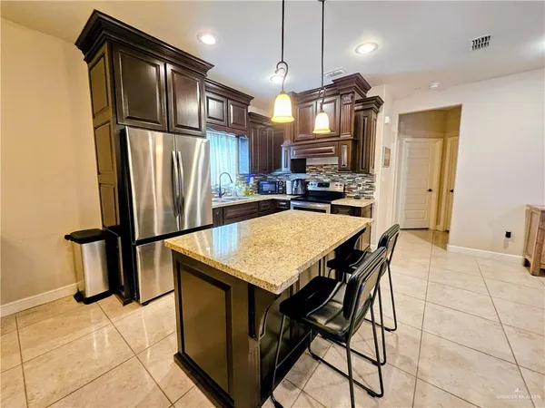 a kitchen with stainless steel appliances granite countertop a refrigerator a stove a sink a dining table and chairs