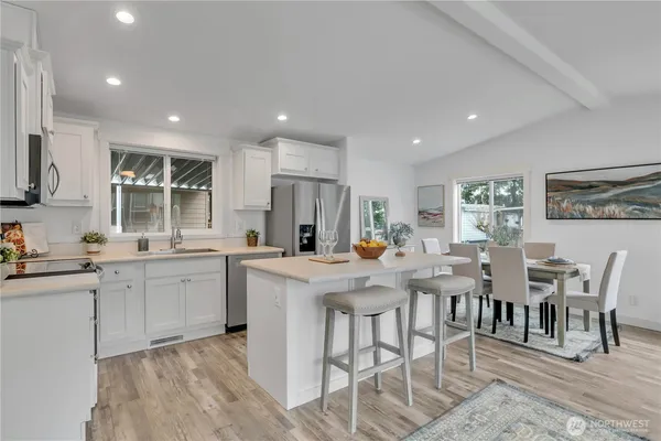 a kitchen with stainless steel appliances a stove a sink a microwave a refrigerator and cabinets