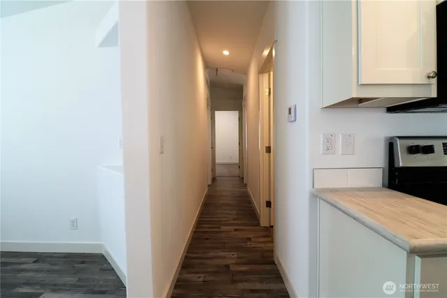a view of a hallway with granite countertop white cabinets and wooden floor