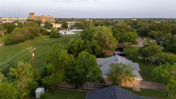 an aerial view of a houses with outdoor space and trees all around