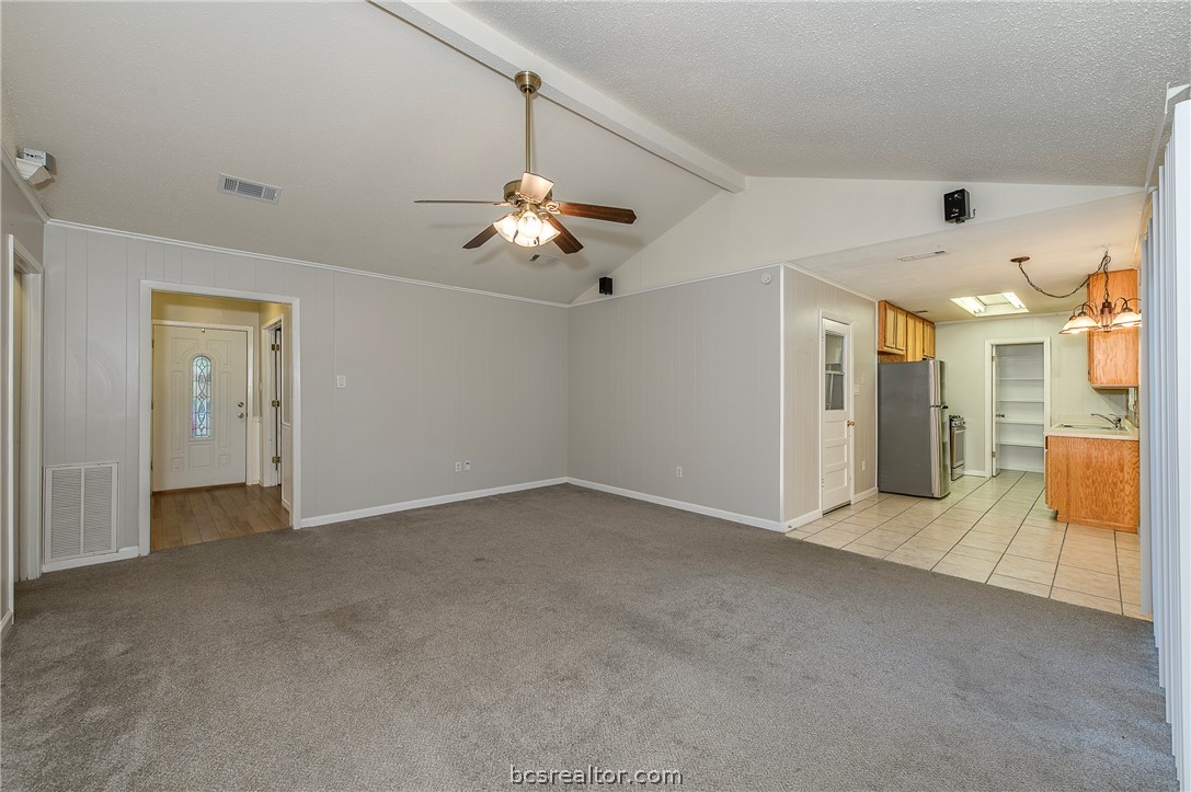 2303 Avon Street Bryan, TX 77802 - Photo 4 of 32 Features include carpet flooring, wood panel wall details, vinyl trim glass sliding door leading to the enormous back yard & patio. Easy access to the dining room, kitchen & exit door to the garage