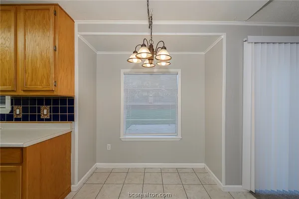 a room with kitchen island a chandelier stainless steel appliances cabinets and a window