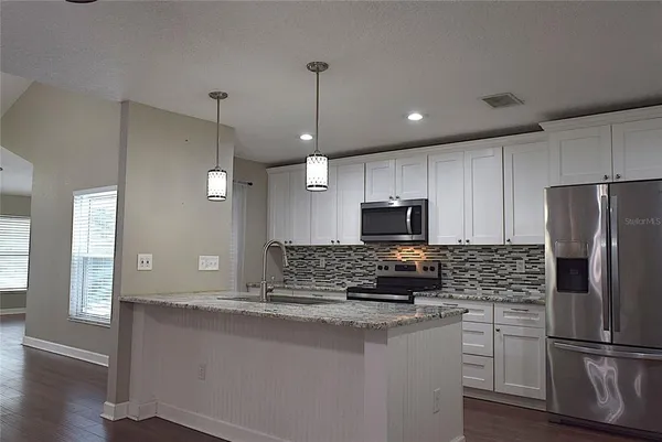 a kitchen with kitchen island a counter top a sink stainless steel appliances and cabinets