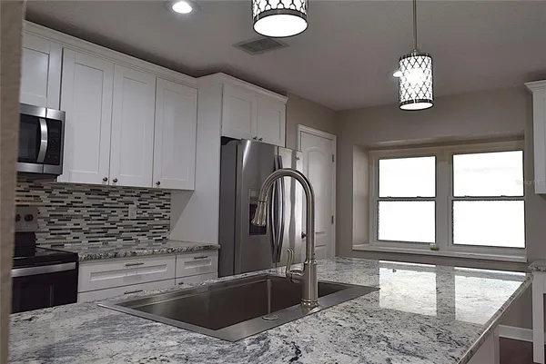 a kitchen with stainless steel appliances granite countertop a sink a stove and refrigerator