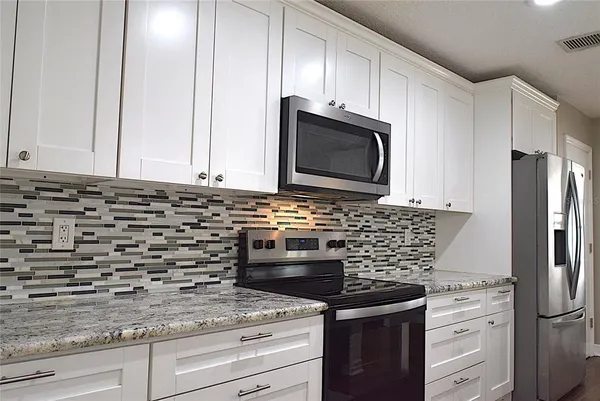 a kitchen with granite countertop white cabinets and stainless steel appliances
