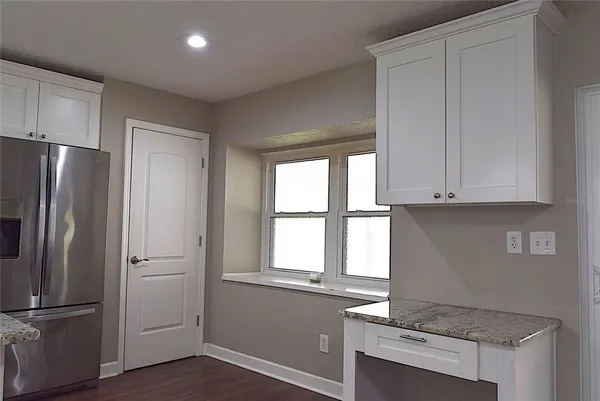 a kitchen with granite countertop stainless steel appliances a refrigerator cabinets and wooden floor