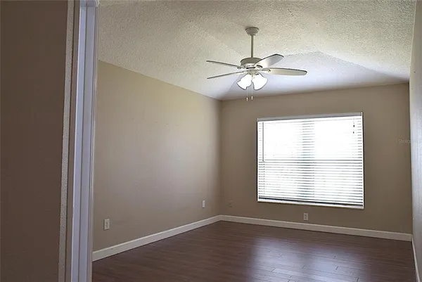 an empty room with wooden floor and a ceiling fan