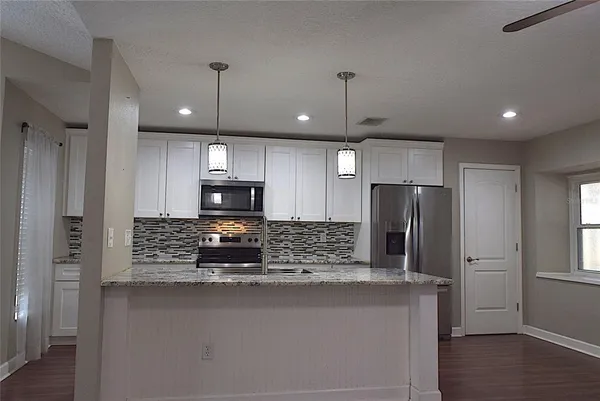 a large kitchen with stainless steel appliances a large counter top