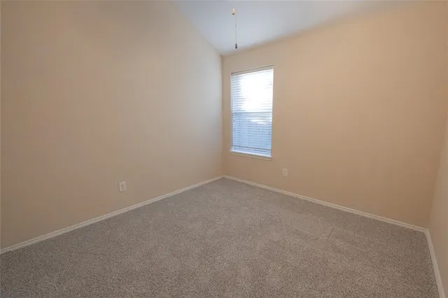 an empty room with a chandelier fan and windows