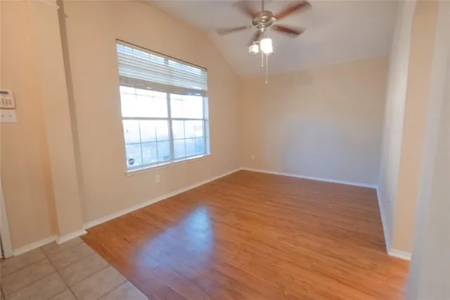 an empty room with wooden floor fan and windows
