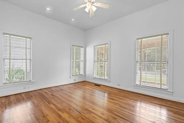 a view of an empty room with wooden floor and a window