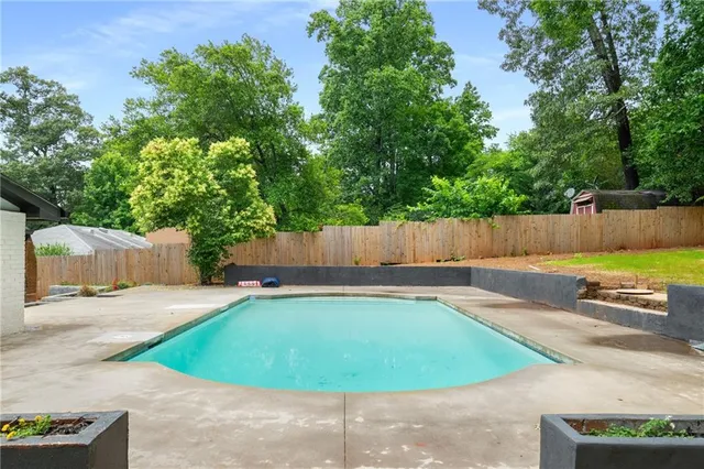a view of a swimming pool with a yard and large trees