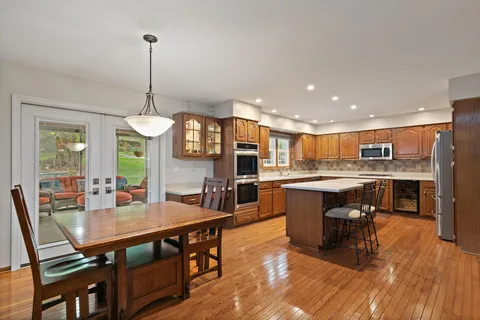 a kitchen with stainless steel appliances granite countertop a stove top oven a sink dishwasher a dining table and chairs with wooden floor