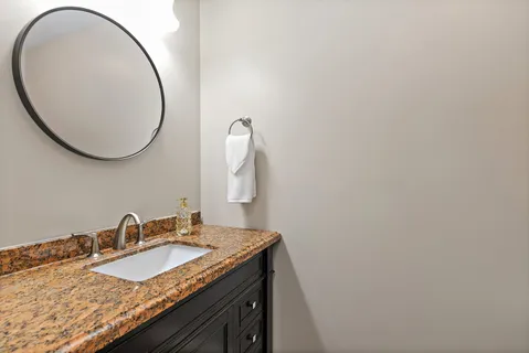 a bathroom with a granite countertop toilet sink and mirror