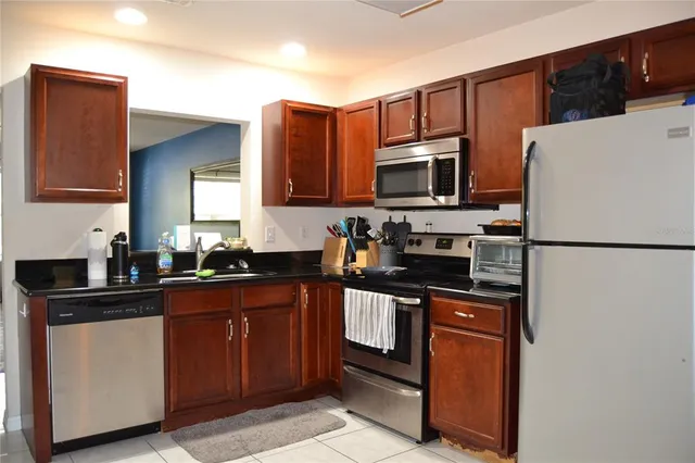 a kitchen with granite countertop a refrigerator stove top oven and sink