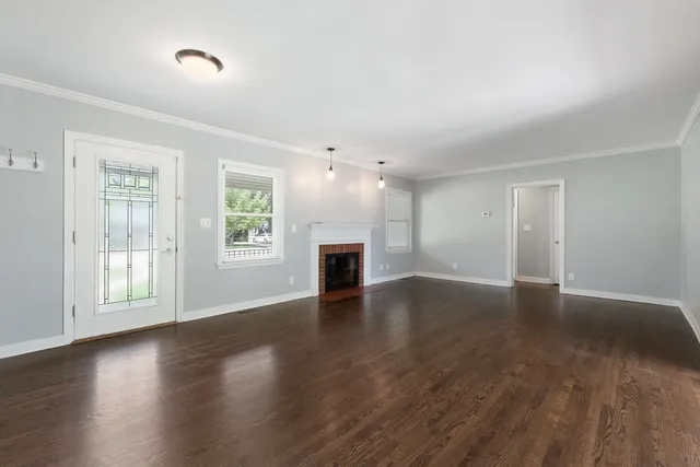 an empty room with wooden floor fireplace and windows