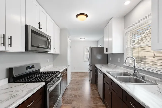 a kitchen with stainless steel appliances granite countertop a sink stove microwave and refrigerator