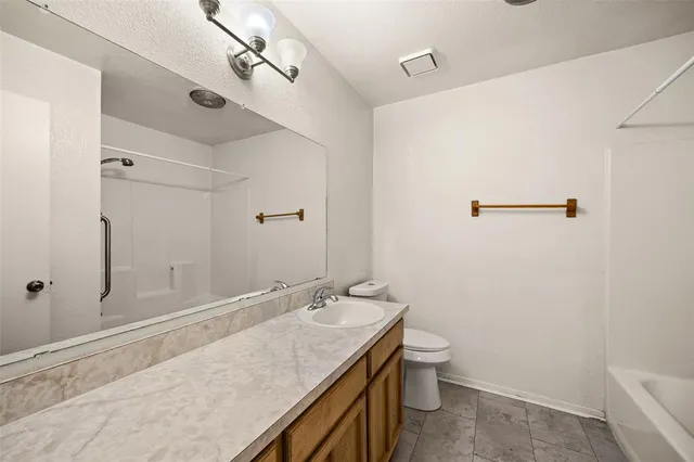 a bathroom with a granite countertop sink a toilet and shower