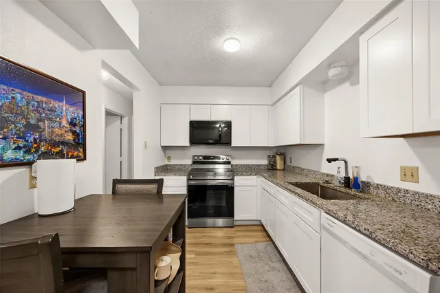 a kitchen with stainless steel appliances granite countertop a sink a stove top oven a counter space and cabinets