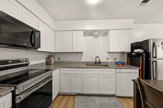 a kitchen with stainless steel appliances granite countertop a sink stove microwave and refrigerator