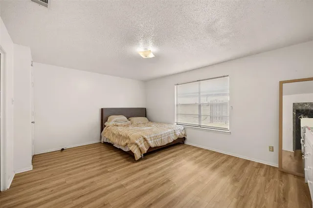 a spacious bedroom with a bed and wooden floor