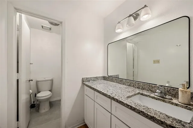 a bathroom with a granite countertop sink a toilet and a mirror