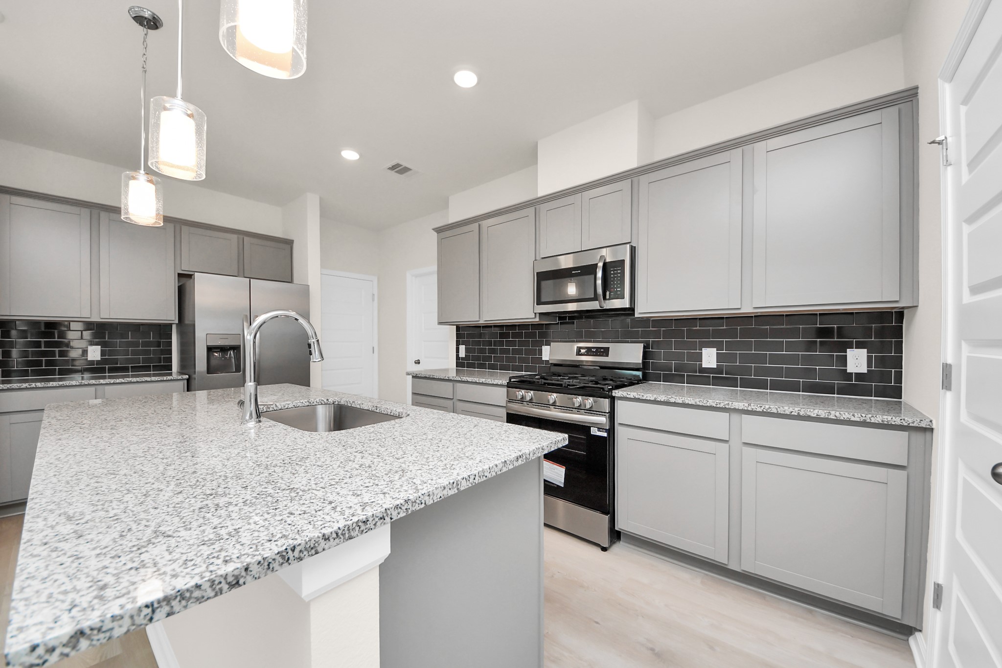 15523 Fathom Line Way Houston, TX 77053 - Photo 7 of 39 Well-appointed kitchen with extensive gray cabinetry offering ample storage space, granite countertops, stainless steel appliances, and a large center island with a sink.