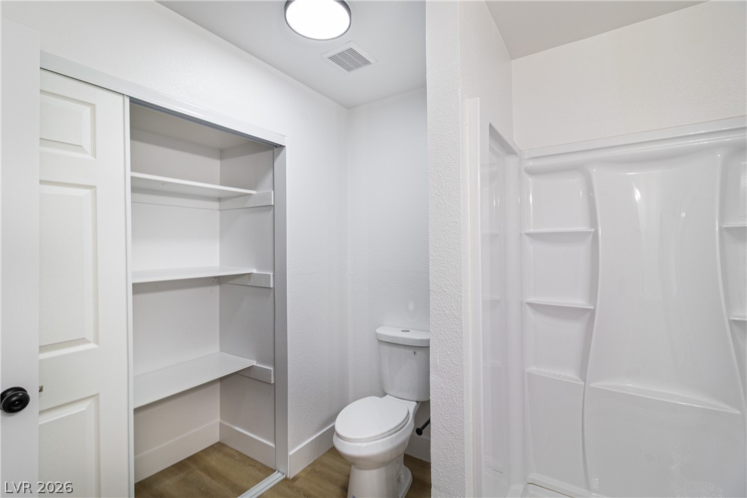 1891 Brian Road Pahrump, NV 89048 - Photo 38 of 50 Bathroom with wood finished floors, baseboards, visible vents, walk in shower, and toilet