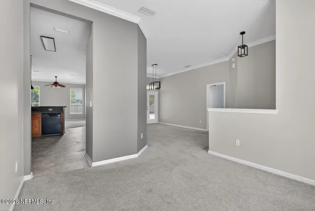 a view of an empty room and chandelier fan